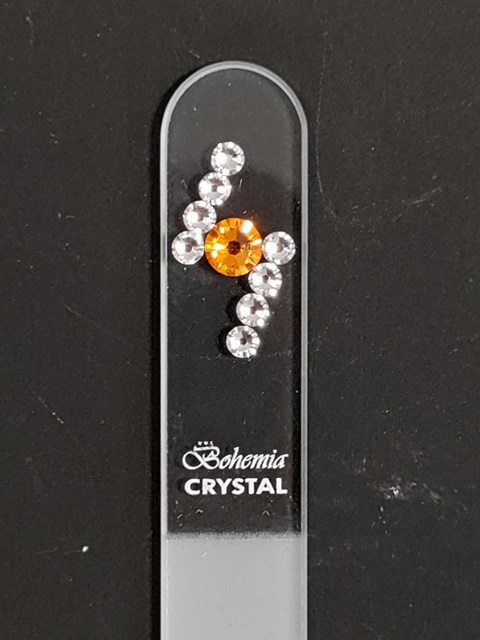 Glazen nagelvijl van 14 cm met oranje en transparante Swarovski stenen. Geleverd met zwart 'fluwelen' hoesje en plastic tube. Ideaal voor luxe nagelverzorging.